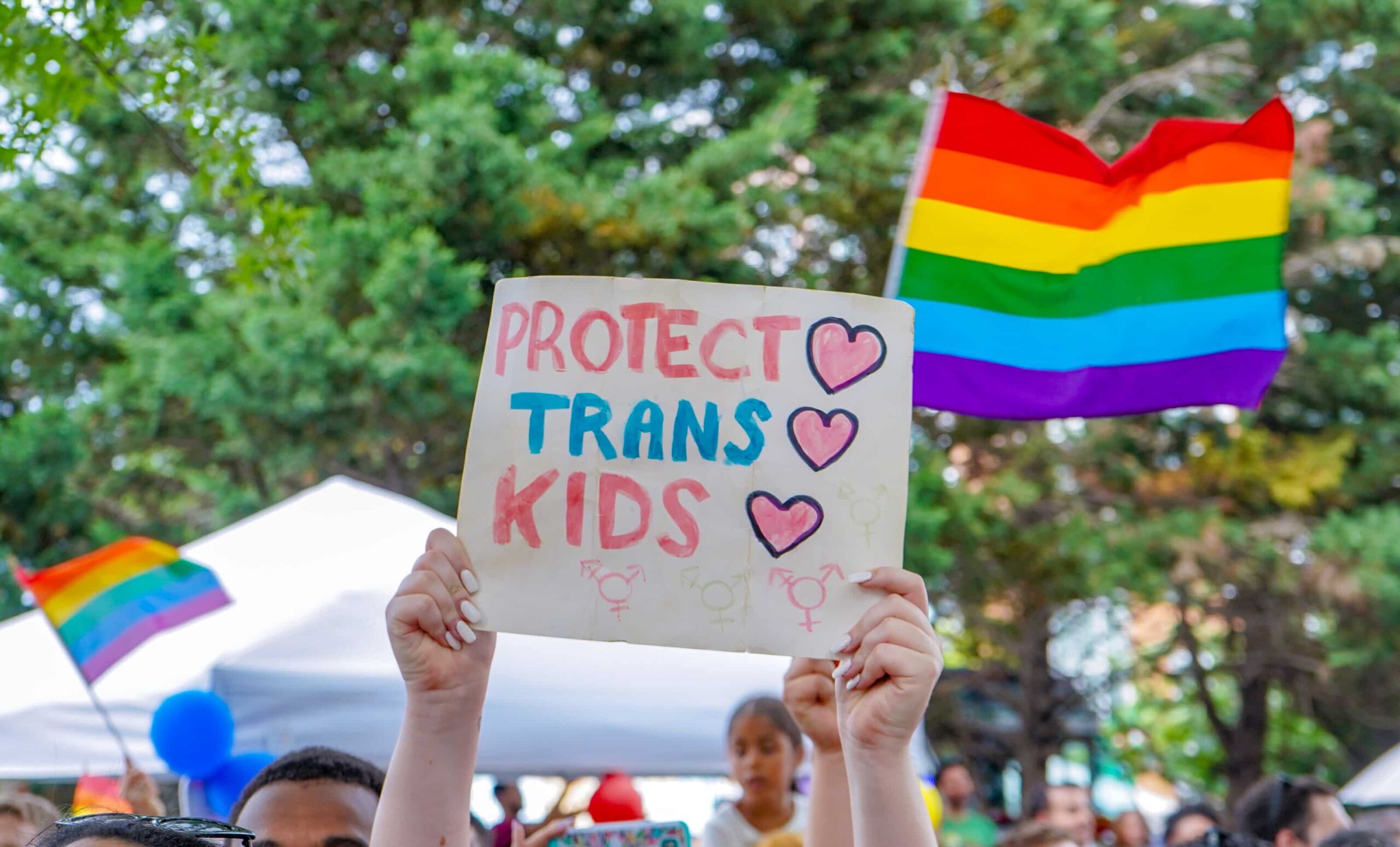 Cartel con mensaje 'Protect Trans Kids' alzado por manifestantes en una marcha por los derechos LGBTIQANB+